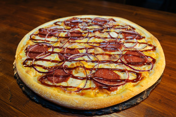 Italian pizza with sausage products on a wooden table