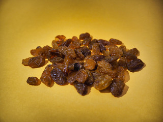 Dried raisins on yellow background