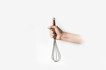 Hand holding a whisk on a white background