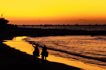 People on horseback during sunset on the beach of M&aacute;ncora Per&uacute;