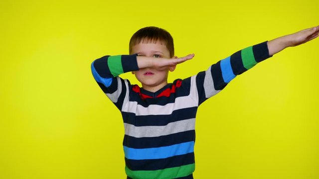Little child boy in a multi-colored sweater shows dance movement deb on yellow background with copy space. Place for text or product. 4K slowmotion footage