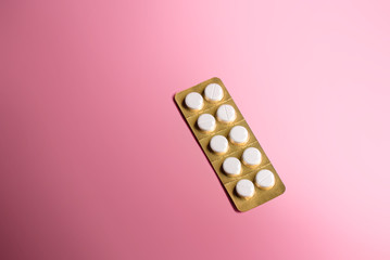 white pill blister pack of 10 pills on a pink background