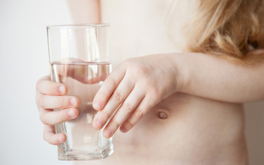 Little caucasian girl holds a glass of drinking water