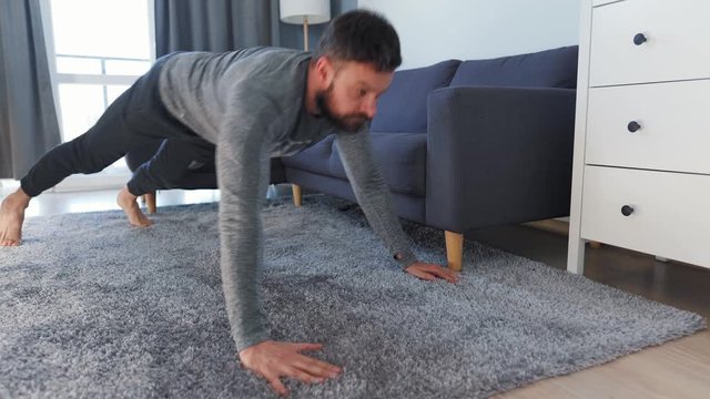 Caucasian man does exercise at home during quarantine due to COVID-19