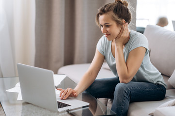 Shopping online. Attractive young girl in home clothes is sitting at home on the couch and shop online using a laptop