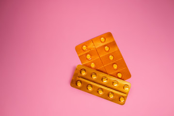 pack sealed orange pill package on a pink background