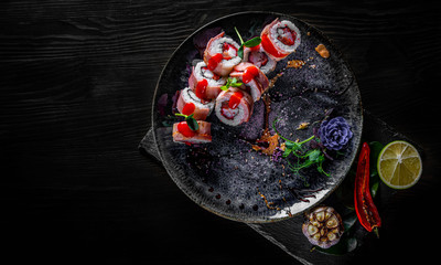 sushi roll with tuna, cream cheese, cucumber, rice in plate on black wooden table background