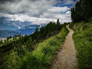 Fototapeta na wymiar Dramatic vintage view of narrow gravel trekking trail, grass close-up across mountain peak