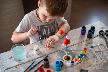 Boy tinkering a model of the solar system Concept of teaching children. Studying astronomy from childhood. Developing creativity from early age. Drawing with brushes and paints. Lockdown entertainment