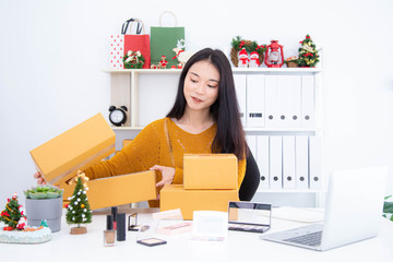 Asian woman prepare the product boxes for deliver to customer. Online shopping, Online selling, e-commerce and freelance working concept.