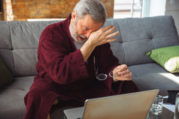 Life goes on around. Senior man during quarantine, realizing how important stay at home during...