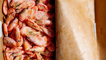 Freshly frozen shrimps in paper box package close-up top view