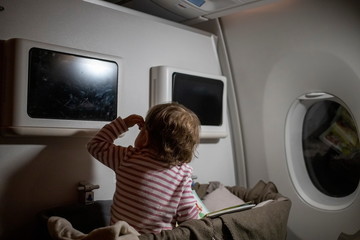 Fototapeta na wymiar comfortable flight with infant. little cute toddler sitting looking at the screen