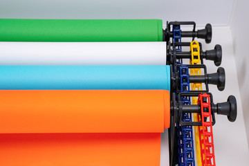 Mounted manual backdrop support system with cross bars and four rolls of colorful paper backgrounds...