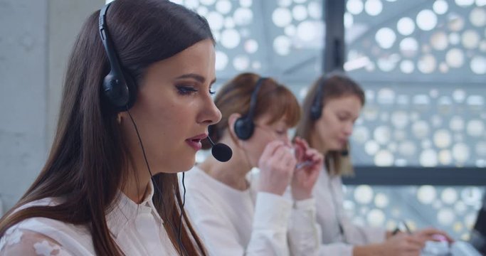Close up of young Caucasian woman in headset speaking with customer in call center. Female operator of online support office. Helping to solve technical issues online Selling managers Teleshop service