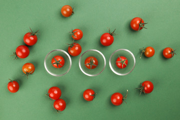 Red ripe cherry tomato with stem on green paper background copy text space mini glass bowl