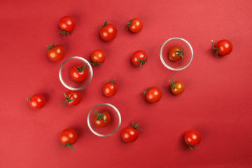 Red ripe cherry tomato with stem on red paper background copy text space mini glass bowl