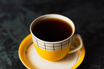 One yellow vintage cup with tea or coffee on a dark background