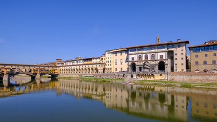 The famous Ponte Vecchio, the Old Bridge and city houses with reflections in the Arno River, Florence, Tuscany, Italy