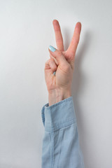 Female hand showing gesture of victoria. Two fingers raised up on white background. Peace and Victory. Vertical frame