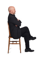 portrait of a man sitting on a chair side view on  white background, lengs and arms crossed