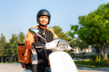Asian man courier on scooter delivering food in town streets with a hot food delivery from take aways and restaurants to home, express food delivery and shopping online concept. © Prasit Rodphan