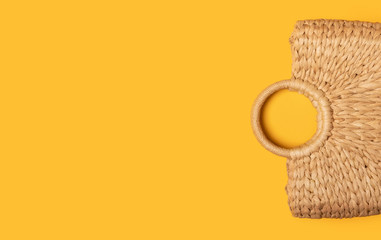 Wicker straw or rattan women's eco bag on yellow background. Flat lay top view. Concept of travel Summer background with copy space. Beach accessori.
