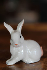 Statue of a white rabbit doll on the wooden table.