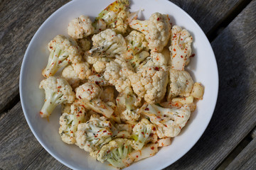 A bowl of spiced cauliflower with red chilli on a plate