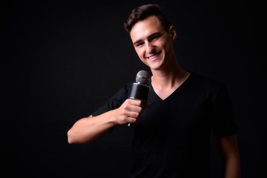 Portrait of happy young handsome man using microphone