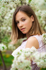 Portrait of a young blonde girl posing in spring park