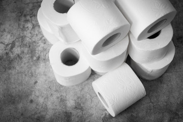 Three rolls of toilet paper on a light grey background. Basic hygiene article shortage
