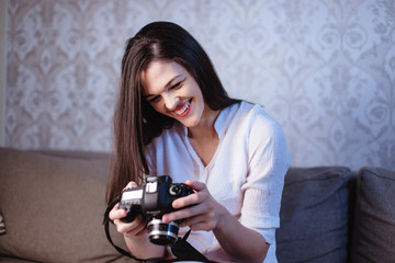 A young female photographer in the evening at home reviewing photos on the camera