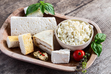Various types of fresh organic goat cheese on rustic wooden table.