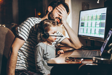 Father and daughter are working on a laptop. businessman working from home and watching the child. A young man works on a computer. Launch. Freelancer concept. Family on quarantine