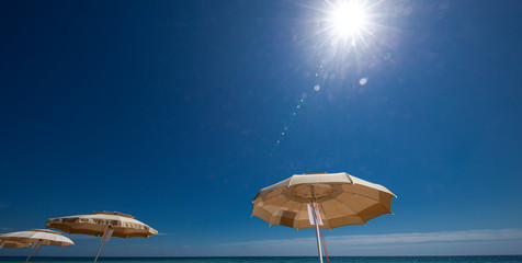 ombrelloni aperti e sullo sfondo mare  e cielo  blu e un motoscafo pronto a partire
