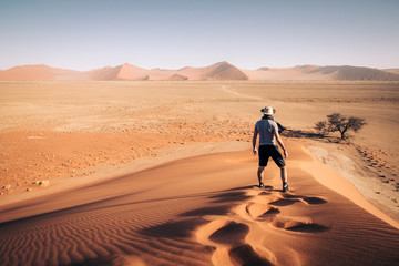 Namibia Namib Desert Sossusvlei Man walking on the top of the famous dunes at sunrise. Epic intrepid adventure travel.