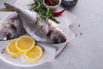 Delicious raw dorado or sea bream fish with lemon spices, fresh rosemary on marble board view from above