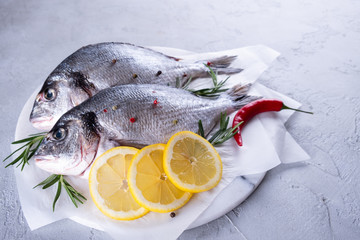 Delicious fresh fish on gray background. Fish with aromatic herbs, spices and lemon - healthy food, diet or cooking concept