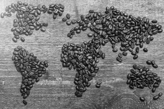Dramatic photo of world map made of arabic roasted coffee beans on old vintage wooden table.