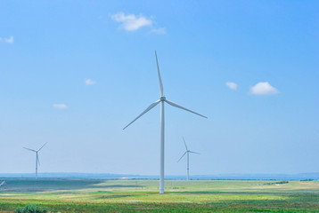 three wind generators on the field on a sunny day