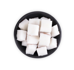 The coconut meat is cut into squares in a black cup ready for cooking. Isolated on white background, Top view