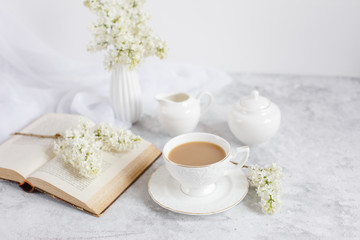a bouquet of white lilac, a Cup of coffee and an old book top view. Postcard good morning.