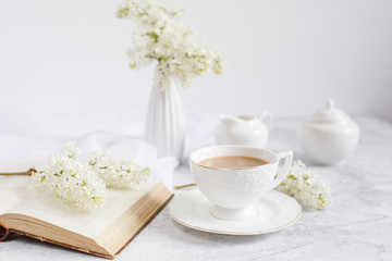 Fototapeta na wymiar a bouquet of white lilac, a Cup of coffee and an old book top view. Postcard good morning.