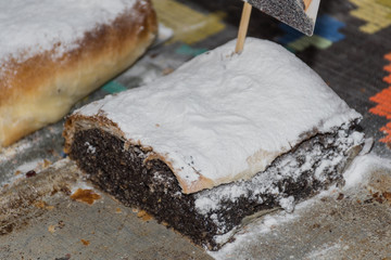 Pie with poppy seeds, powder sugar coating, during food festival, street food. Traditional dish