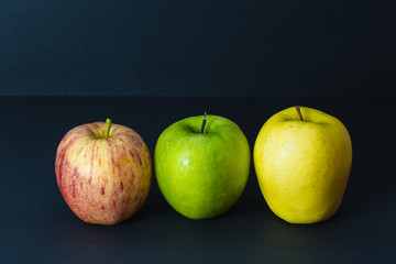 3 different colors of apples on black background