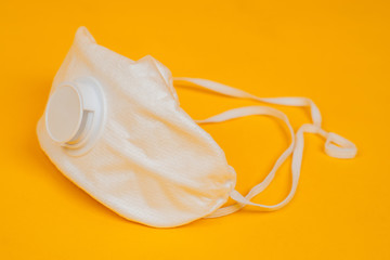White medical mask on an orange background. Respiratory protection against viruses and bacteria. Prevents dust from entering the nose and mouth. Flu epidemic.