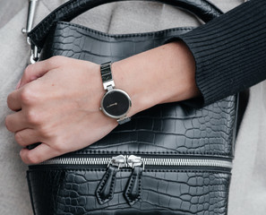 close-up hand of a girl with a clock on the background of a bag