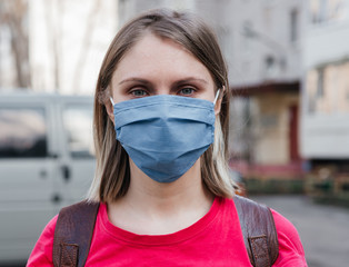 .Close-up young girl with short hair in a blue mask on the street. Coronavirus
