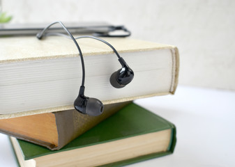 Close up  earphones and stack of books on desk. Audiobook concept Modern education listening to book. Banner. Copyspace.